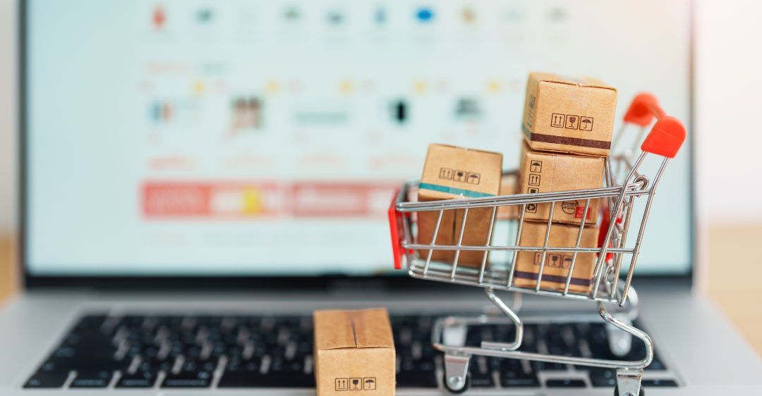  Einkaufswagen mit Paketen vor Online-Shopping-Seite.